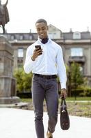 Young African American businessman using a mobile phone on a street photo