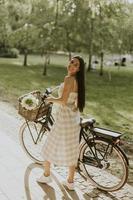 mujer joven con flores en la cesta de la bicicleta eléctrica foto