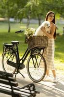 mujer joven con perro bichon frise blanco en la cesta de la bicicleta eléctrica foto