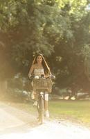 mujer joven con flores en la cesta de la bicicleta eléctrica foto