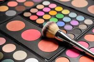 Decorative cosmetics for eye makeup, pallets with bright colors and cosmetic drawing brush photo