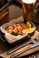 Roasted king prawns with lemon in a bowl and a glass of beer photo