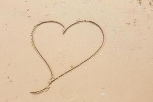 heart drawn in the smooth beach sand. love concept photo