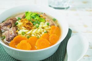 Macaroni soup with pork and carrot on white wooden table - delicious and healthy food concept photo
