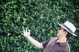 Portrait Asian tourist man over green tree wall background - tourist advertising travel concept photo