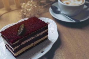 Red velvet cake with hot coffee cup on wooden table photo