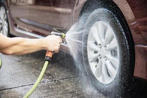 El hombre lava el coche con champú - concepto de cuidado del coche de la vida cotidiana foto