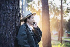 Asian man with mobile phone in forest tree nature - people in spring nature and technology concept photo