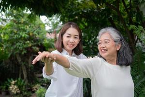 An old elderly Asian woman and exercise in the backyard with her daughter.  Concept of happy retirement With care from a caregiver and Savings and senior health insurance, Happy family photo