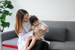 Asian female dentist teaching cute little girl brushing teeth with toothbrush and stomatologist telling girl child about oral hygiene in dental clinic, Education and prevention cavities concept. photo