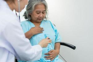 Physician examining heart with a stethoscope and talking with a senior woman at a clinic for check yearly checkup, Medicine health care service and medical insurance concept. photo