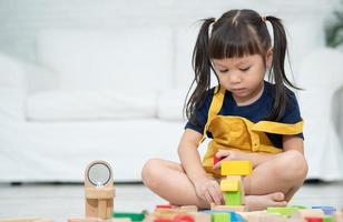 linda niña asiática jugando con coloridos bloques de juguete, los niños juegan con juguetes educativos en el jardín de infantes o en la guardería. juego creativo del concepto de desarrollo infantil, niño pequeño en la guardería. foto