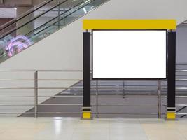 Blank white billboard black frame ad horizontal beside at escalator in the airport terminal photo