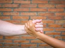 Close-up image of shaking hands between man and woman with brick background photo