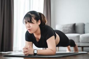 Asian chubby young woman doing planking exercise indoors at home . photo