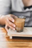 la mujer sostiene un vaso de espresso sobre leche fresca fría. café sucio, menú de café, café con leche foto