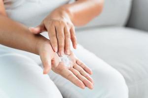 mujer aplicando crema hidratante de loción corporal en sus manos. foto