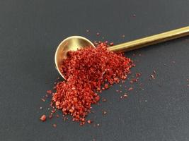 A spoonful of Red Pepper Powder black background. Selective focus photo