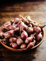 red onion or Shallots. shallots on wooden plate with . Selected focus. Concept of spices in healthy cooking photo