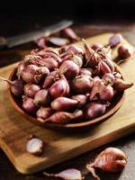 red onion or Shallots. shallots on wooden plate with . Selected focus. Concept of spices in healthy cooking photo