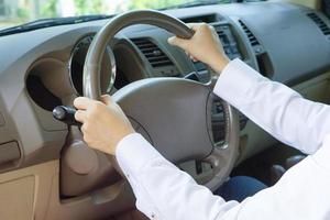 la mano del hombre usa camisa blanca sosteniendo el volante mientras conduce un camión. foto