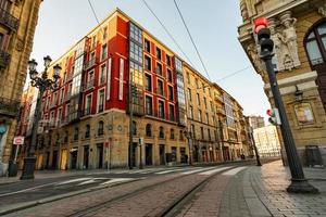 BILBAO, SPAIN-DECEMBER 19, 2021 Old building and empty tramway track for city tram. Citysacpe of Bilbao, Spain. Smart city. Red traffic light on pole. Landmarks in Spain. Sustainable transport. photo