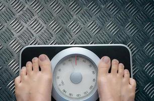 Top view of feet on weighing scale. Women weigh on a weight balance scale after diet control. Healthy body weight. Weight and fat loss concept. Weight measure machine. Body Mass Index or BMI concept. photo