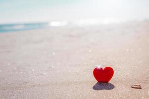 Romantic symbol of red heart on the sand beach photo