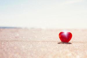 Romantic symbol of red heart on the sand beach photo