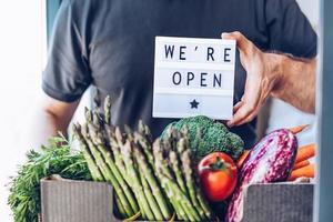 texto que estamos abiertos y caja de verduras y verduras frescas foto