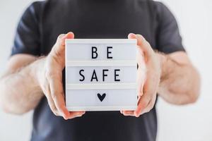 Man holding lightbox with text Be safe in his hand photo