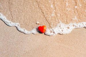 símbolo romántico de corazón rojo en la playa de arena foto