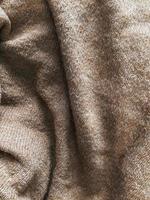 Brown fabric cloth texture background with wavy folds and shadows, closeup, vertical photo. Abstract textile material, cozy and warm wallpaper design, top view photo