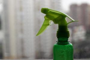 Green sprayer for home plants and flowers closeup, horizontal photo on blurred background. Single design element with empty space for text, plastic bottle, gardening accessory