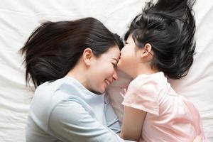 Daughter kisses her mother's forehead. and hugging in the bedroom . photo