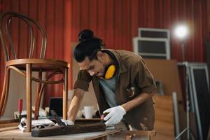 Young Asian man Carpenter working in woodcraft carpentry workshop. photo