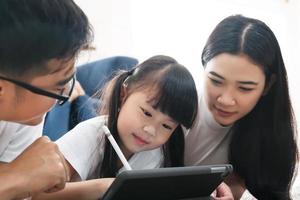 hija usando tecnología educativa de aprendizaje de tabletas con la familia. foto