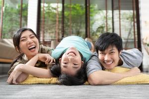 retrato de una familia asiática feliz pasando tiempo juntos en un sofá en la sala de estar. concepto de familia y hogar. foto