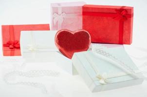 chocolate con forma de corazón rojo con pequeñas cajas de regalo y decoración de cinta - concepto de decoración de amor y regalos foto