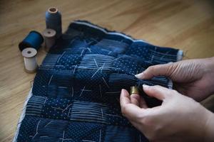 mujer vintage cosiendo tela a mano con bordados sobre fondo de mesa de madera - gente y concepto de tareas domésticas hechas a mano foto