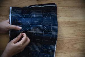 mujer vintage cosiendo tela a mano con bordados sobre fondo de mesa de madera - gente y concepto de tareas domésticas hechas a mano foto