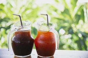 Ice coffee and tea on wooden table over green garden background - relax with beverage in nature concept photo