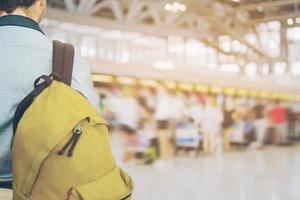 Soft focused picture of traveler over blurred long passenger queue waiting for check-in at airport check-in counters photo