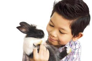 Asian kid playing with lovely baby rabbit isolated over white photo