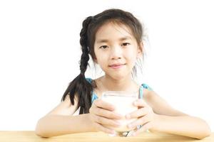 Chica asiática está bebiendo un vaso de leche sobre fondo blanco. foto