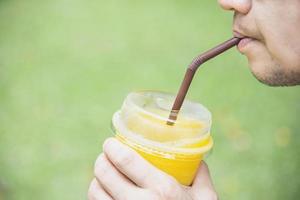 Man drink ice mango orange blend in green garden - relax people with cold fruit drink concept photo