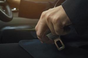 Man putting car seat belt before driving, close up at belt buckle, safe drive concept photo