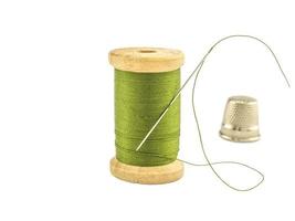 Isolated wooden spool of green thread with a needle photo