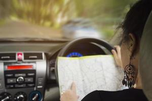 la mujer está mirando peligrosamente un mapa mientras conduce un automóvil foto