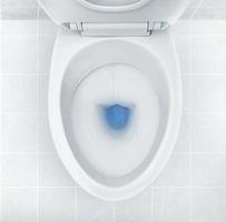 Top view of toilet bowl, blue detergent flushing in it photo